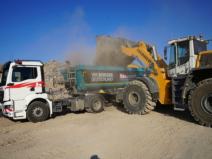 Bagger belädt LKW mit Recyclingmaterial